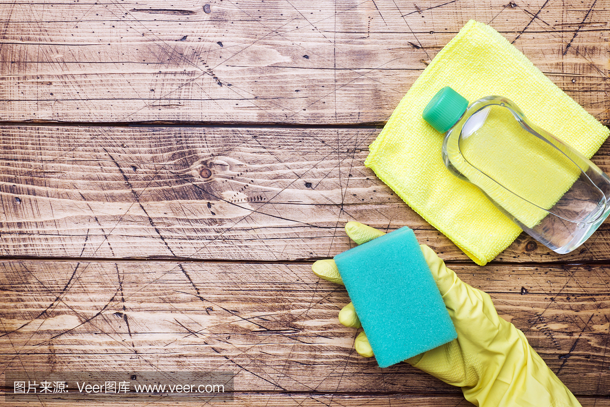 将黄色手套和清洁海绵交于清洁木质背景。家庭清洁的概念。俯视图,复制空间
